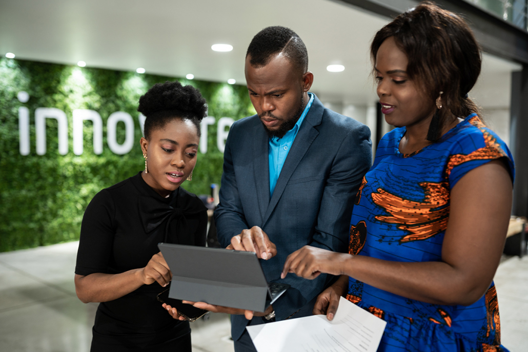 African businesspeople using a tablet together in an office lobby